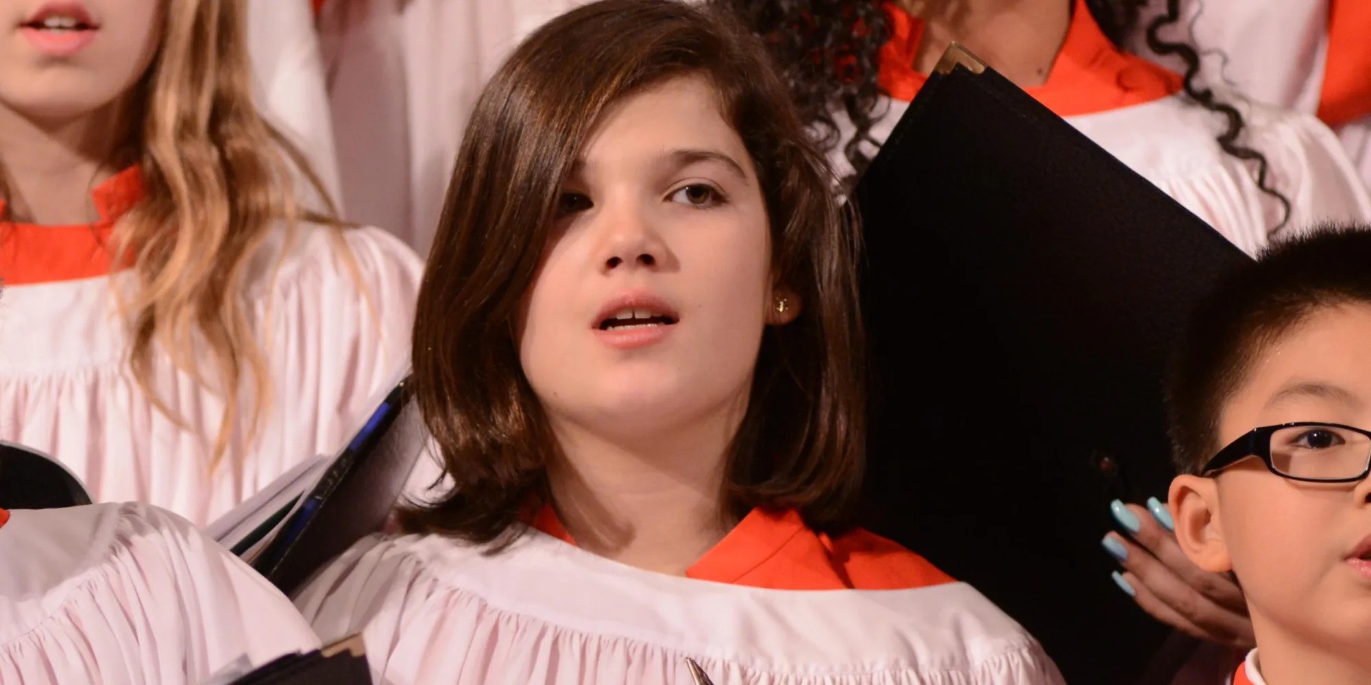 Trinity Youth Chorus members in white and red robes singing