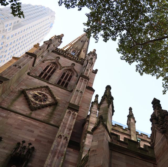 Trinity Church's steeple, seen through leaves and branches of trees in the Churchyard.