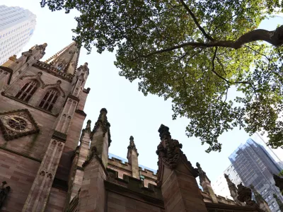 Trinity Church's steeple, seen through leaves and branches of trees in the Churchyard.