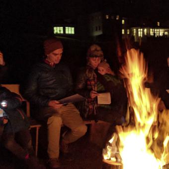 A group of families gather at the bonfire.
